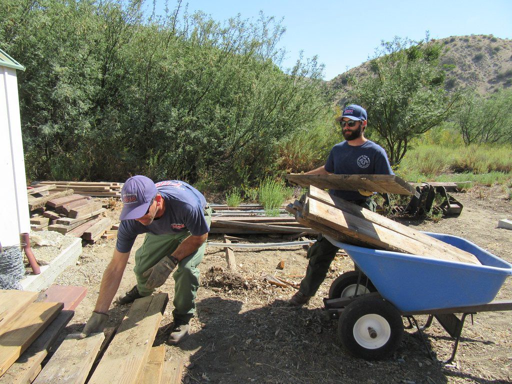 Volunteers rebuilding a trail with lumber and a wheelbarrow